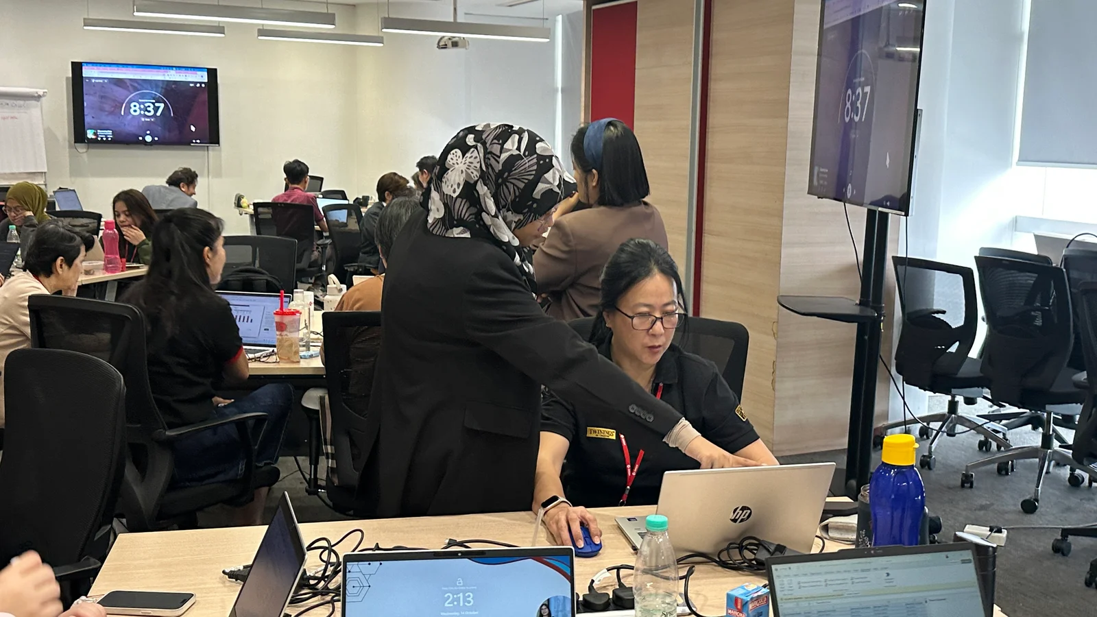 A facilitator guiding a participant through an exercise on her laptop during private team training.